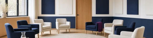 Empty recovery group room with a circle of navy and cream chairs, a purple throw, and a closed privacy door