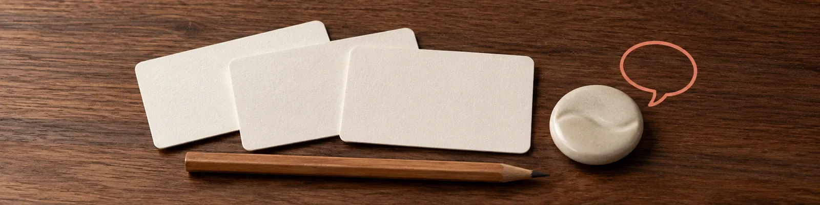 Close photo of blank question cards and a pencil beside a small illustrated speech-loop motif.