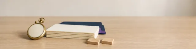Brass stopwatch beside blank assessment cards, wooden sorting tiles, a navy folder, and a purple scoring tab