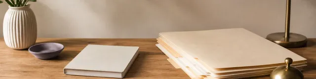 Calm therapy office desk with folder tabs, closed notebook, brass paperweight, and soft lamp light for insurance billing workflow planning