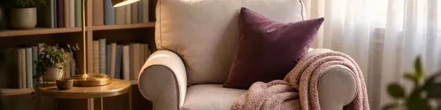 A single reading chair with a warm lamp and folded throw in a calm, softly lit therapy office nook