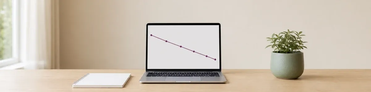 Open laptop showing a descending purple therapy outcome trajectory beside a blank notebook and potted plant on a light oak desk