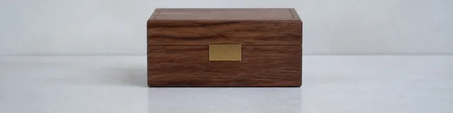 Cool north morning light on a pale stone shelf with one closed walnut index box and a single unused brass tab