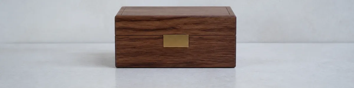 Cool north morning light on a pale stone shelf with one closed walnut index box and a single unused brass tab