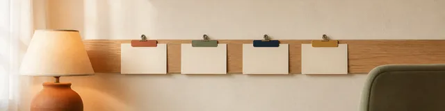 Empty small-practice supervision room with a terracotta lamp, oak wall rail holding four blank cream cards with terracotta sage navy and gold clips, and a sage chair back