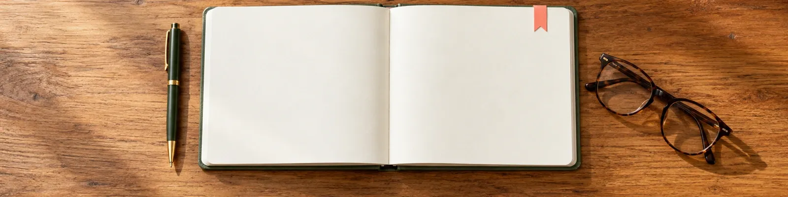 Warm desk photo of a blank notebook and pen with a small coral note-marker illustration.