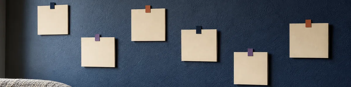 Six blank cream activity cards with navy, violet, and terracotta tabs on a softly lit community-room wall beside one chair edge