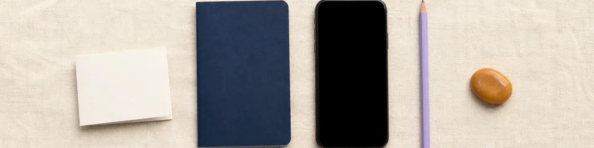 Blank folded wallet card, navy notebook, phone, lavender pencil, and amber grounding stone arranged on cream linen