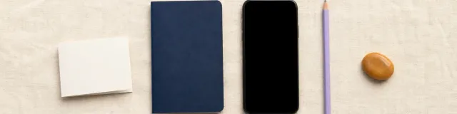 Blank folded wallet card, navy notebook, phone, lavender pencil, and amber grounding stone arranged on cream linen