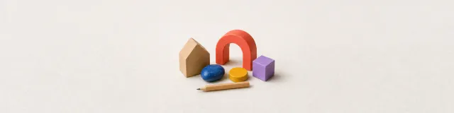 Close-up of a wooden house, colorful tactile choice objects, and a pencil on pale felt