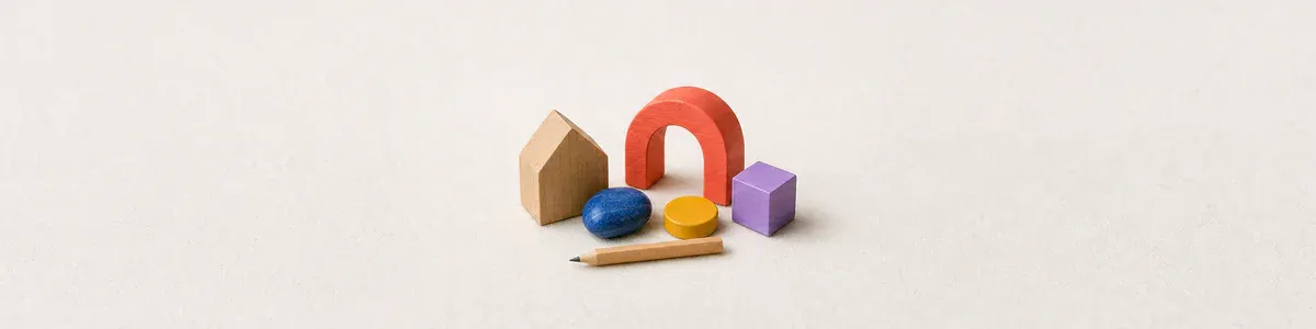 Close-up of a wooden house, colorful tactile choice objects, and a pencil on pale felt
